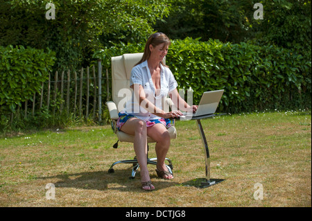 Garden office woman working on a computer outside during summer Stock Photo