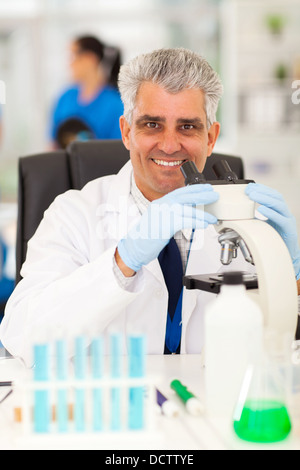 smiling senior scientist working on microscope in lab Stock Photo