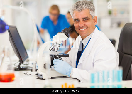 smart middle aged scientist using microscope in the lab Stock Photo