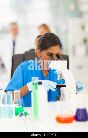 young Indian scientist looking through microscope at the lab Stock Photo