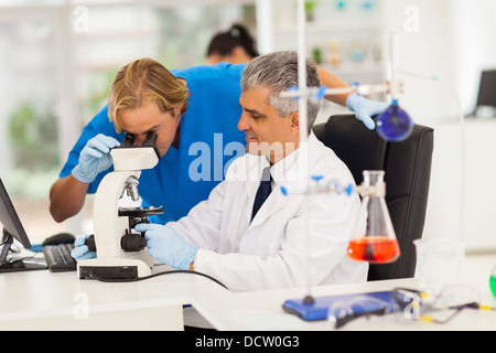 two male medical researchers working with microscope in lab Stock Photo