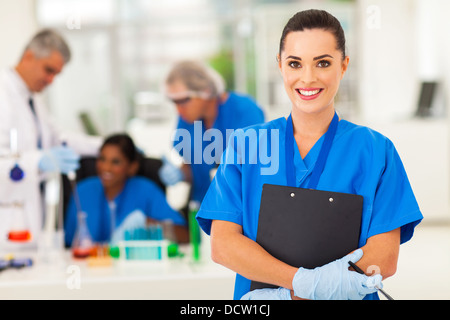 attractive young female lab technician in lab with colleagues Stock Photo
