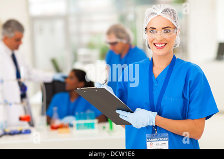 cheerful female medical researcher writing report after doing lab experiments Stock Photo