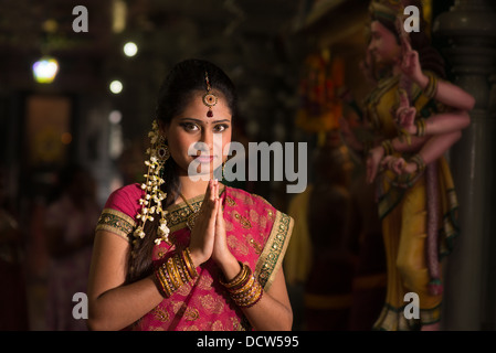 Young Indian girl in traditional sari dress praying in a hindu temple. Stock Photo