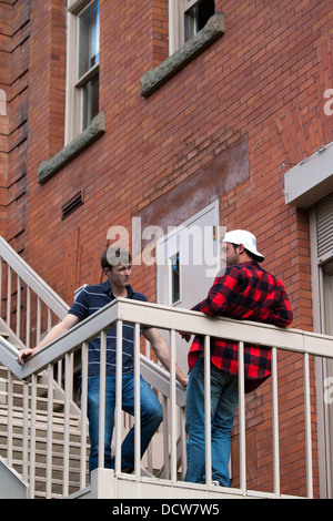 Two young men in a serious discussion on a balcony Stock Photo