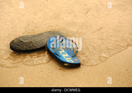A pair of beach shoes laying discarded on a sandy beach Stock Photo
