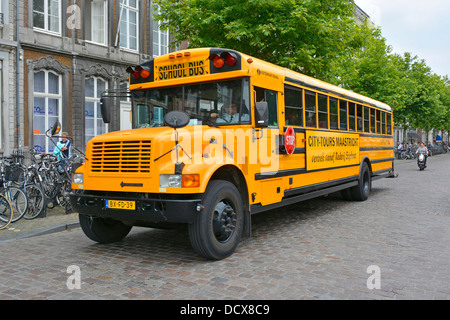 Maastricht City urban street scene side front view yellow American school bus adapted for town centre sightseeing tours Limburg Netherlands Europe Stock Photo