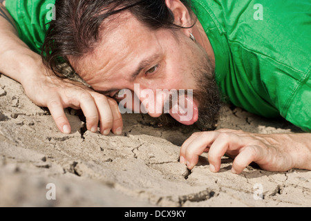 Thirsty long haired man on parched soil Stock Photo