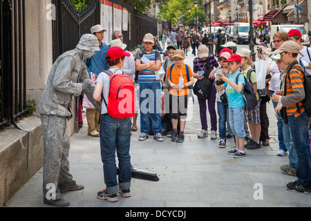 Group of school kids interacting with a street actor in Paris, France Stock Photo