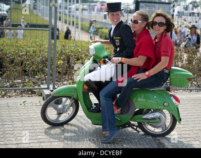Herning, Denmark, Germany. 22nd Aug, 2013. German dressage riders Helen Langehanenberg and Isabell Werth sit on a motor scooter with team veterinarian Cordula Gather after the team competition of the FEI European Championships in Herning, Denmark, Germany, 22 August 2013. The German team finished first. Photo: Jochen Luebke/dpa/Alamy Live News Stock Photo