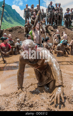 US Military service members crawl through the mud as they join civilians as they participate in Hawaii's first ever Spartan Race 5k obstacle course August 17, 2013 in Kualoa Ranch, HI. Stock Photo
