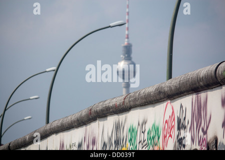 Section of Berlin Wall with graffiti and Fernsehturm TV Tower in distance Berlin Germany Stock Photo