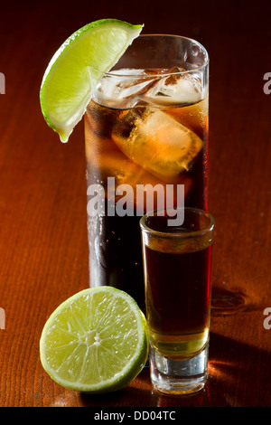 cuba libre, rum and cola cocktail served in a tall glass with a lime garnish and a shot of rum on the side Stock Photo