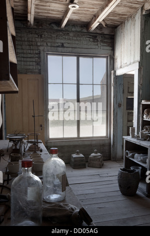 Hotel :part of kitchen, storage room with artefacts, and street seen through window, desaturated image,  Bodie pioneer village,