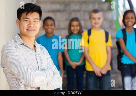 handsome male elementary educator with students on background Stock Photo