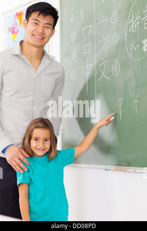 preschool girl with teacher pointing chinese language answer on chalkboard Stock Photo