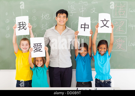 friendly male chinese teacher with group multiracial primary students holding papers saying i love chinese Stock Photo