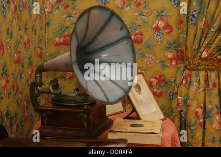 Old portable wind-up gramophone loudspeaker in living room with floral wallpaper decoration Stock Photo