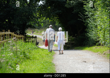 Elderly senior couple walking on a countryside footpath England uk Stock Photo