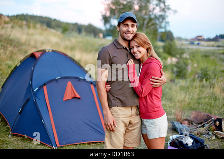 Photo of resting couple looking at camera in the countryside with tent on background Stock Photo