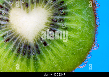 Closeup of a heart shaped kiwi slice covered in water bubbles Stock Photo