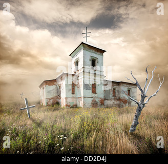 Abandoned church near the cemetery in a field Stock Photo