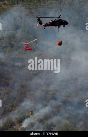 Buck Meadows, CA, USA. 23rd Aug, 2013. A National Guard Black Hawk along with another helicopter work together to slow the spread of the Rim Fire along the east ridge of the Tuolumne River near Pine Mountain Lake CA The Rim Fire in the Stanislaus National Forest along Highway 120 continues to grow. According to the US Forest Service as of Friday Aug. 23rd 2013 afternoon the fire has grown to 125,620 acres with only 5% containment with more evacuations in Tuolumne City, CA and nearby areas along the Highway 108 corridor. The fire continues to spread in several directions including towards Yose Stock Photo