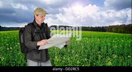 Photographer hiker with map against fields and nature Stock Photo