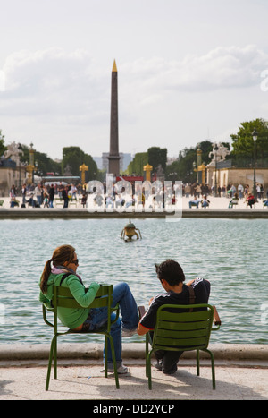 A couple sit in Jardin des Tuileries in front of Luxor Obelisk, Paris, France Stock Photo