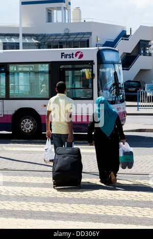 Two people, one in Burka, walking towards a bus, Portsmouth, Hampshire, England Stock Photo