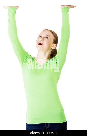 Smiling young woman is holding something abstract above her head. Happy girl with raised hands. Isolated on white background.  Stock Photo