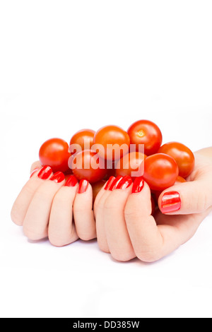 Two hands with orange nails holding cherry tomatoes Stock Photo