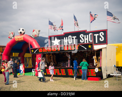 A shooting gallery at a traveling funfair with tattered American and confederate flags flying Stock Photo