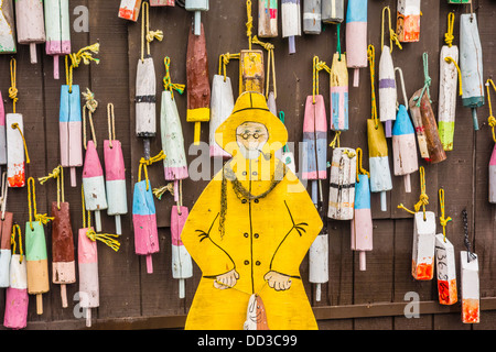 Colorful buoys used in fishing for lobster and crab hang from the side of a building in Maine. Stock Photo