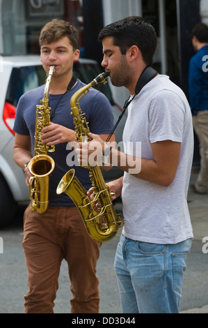 street performers two young men playing sax on the streets of Brecon during Brecon Jazz Festival 2013 Stock Photo
