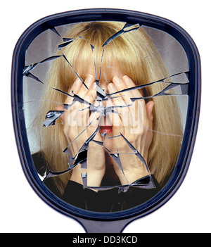 A woman covers her face reflected in a broken mirror or the shattered life concept Stock Photo