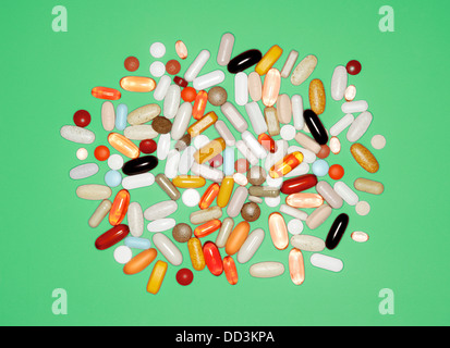 A loose collection of various pills, tablets and capsules on a green background