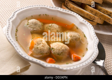 Traditional Jewish passover dish matzah ball soup served with rye bread Stock Photo