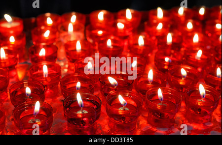 Firing candles in catholic church in red chandeliers Stock Photo