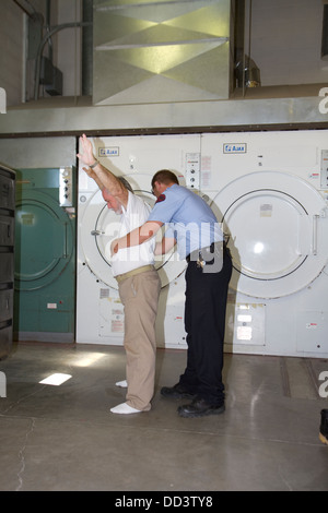 Sergeant pat searching inmate working in laundry. American maximum security prison. Stock Photo