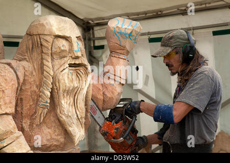 Chainsaw artist at work in Tabley, Cheshire, UK August, 2013. Viking figure face carved by Bruce Thor from the USA at the 9th English Open Chainsaw Carving Competition, chainsaw carving, garden sculpture, statue, woodland, forest crafts at the Cheshire County Showground, Game and County Fair, UK.  The chainsaw art carvers use wood (sometimes huge bits) to produce beautiful carvings of up to 20 feet high. when each one becomes a sought after work of art. Wood sculpture, sawdust, sculptor, timber, chips, log, professional, working, art, artist, cut, chain saw, artwork made from rough timber. Stock Photo