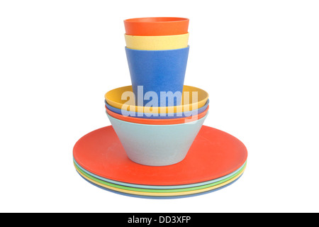 Colorful cups set up on top of piled plates and bowls isolated on white Stock Photo