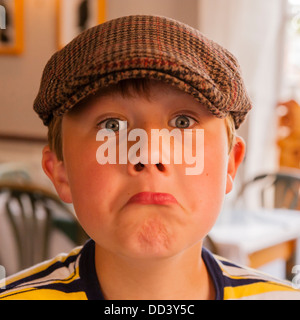 A 9 year old boy wearing a cap and pulling a funny face in the Uk