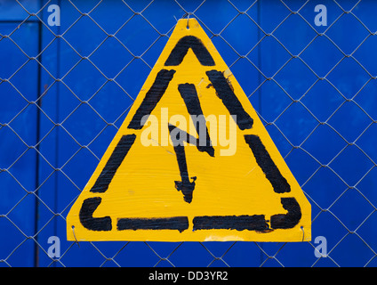 High voltage yellow sign mounted on blue metal rabitz grid Stock Photo