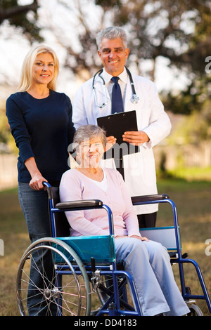 happy disabled senior woman on wheelchair and daughter meeting retirement village doctor outdoors Stock Photo