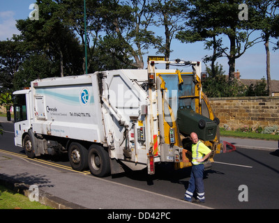 Man working at the rear of a waste disposal vehicle emptying a wheelie bin of garden waste for recycling Stock Photo