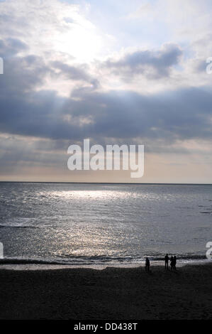 Aberystwyth, Wales, UK. 25th Aug, 2013. Visitors watch sun rays emerge from behind high cloud across Cardigan Bay - as the afternoon sun lights Aberystwyth's North Beach on Bank Holiday Sunday - 25 August 2013. Photo credit: John Gilbey/Alamy Live News. Stock Photo