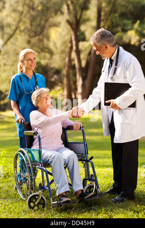 friendly male doctor greeting senior patient outdoors Stock Photo