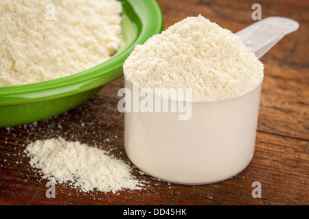 https://l450v.alamy.com/450v/dd45hk/measuring-scoop-of-whey-protein-powder-with-a-bowl-on-wooden-surface-dd45hk.jpg