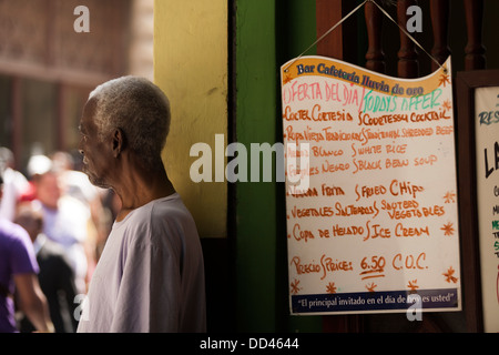 A man looking hungry stands by the menu to a tourist restaurant in Havana, Cuba Stock Photo